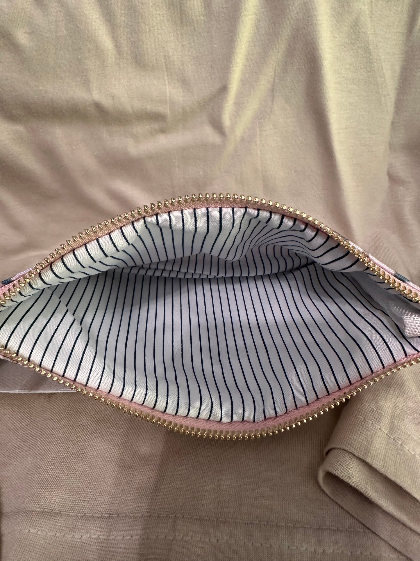 Close-up of a striped fabric inside a bag with a gold zipper on a beige background