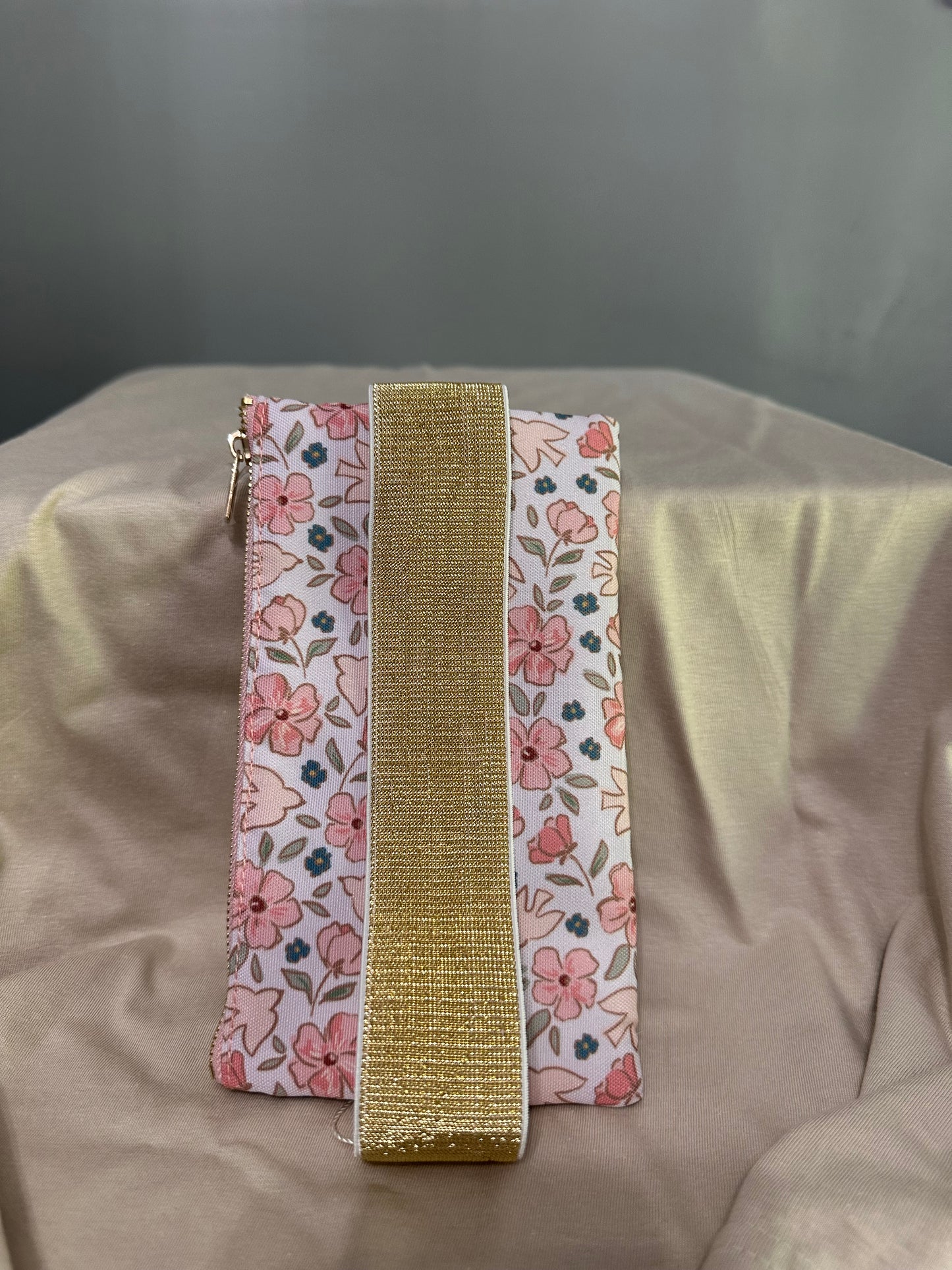 Two floral-patterned ribbons with a gold band on a beige fabric background